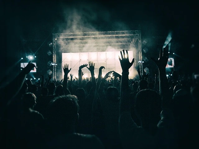 crowd with hands raised in front of concert stage with mist